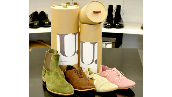 写真：自社ブランド「U.（ユードット）」は遊びがコンセプト。 筒状の箱に靴（ブーツも！）が入るようになっている。箱の取っ手の色は靴の色と一致する。国内外で販売。