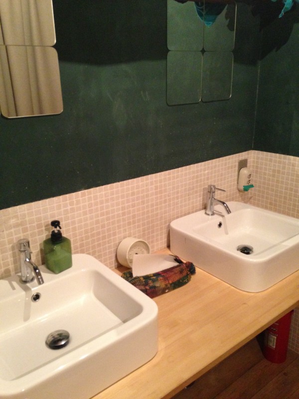 2階にある洗面スペース。壁は黒板塗料で深緑。洗面もタイルも鏡も四角に。